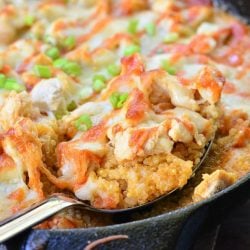 Black skillet filled with creamy siracha chicken and quinoa bake on a wooden table