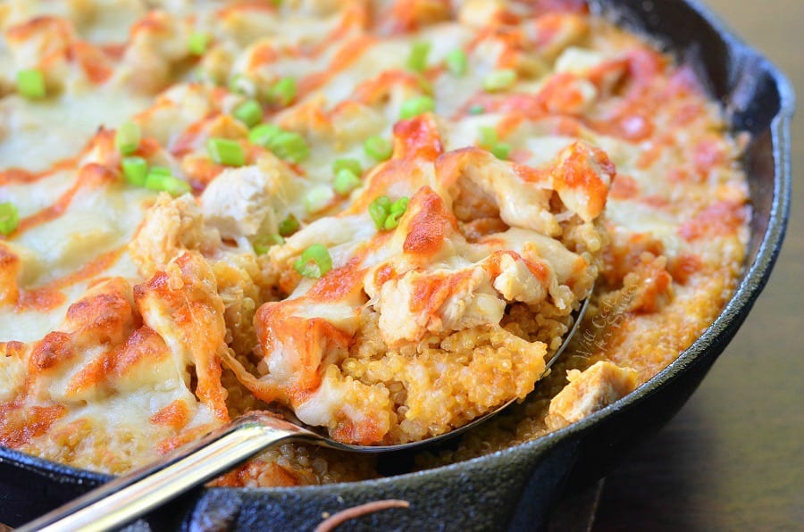 Creamy Sriracha Chicken and Quinoa Bake in a cast iron skillet with a spoon lifting some out 