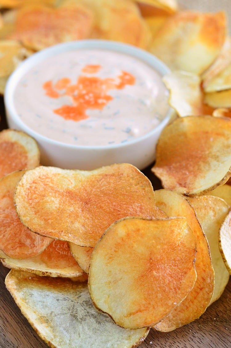 a pile of crispy homemade potato chips spread around and buffalo ranch dip in the middle.