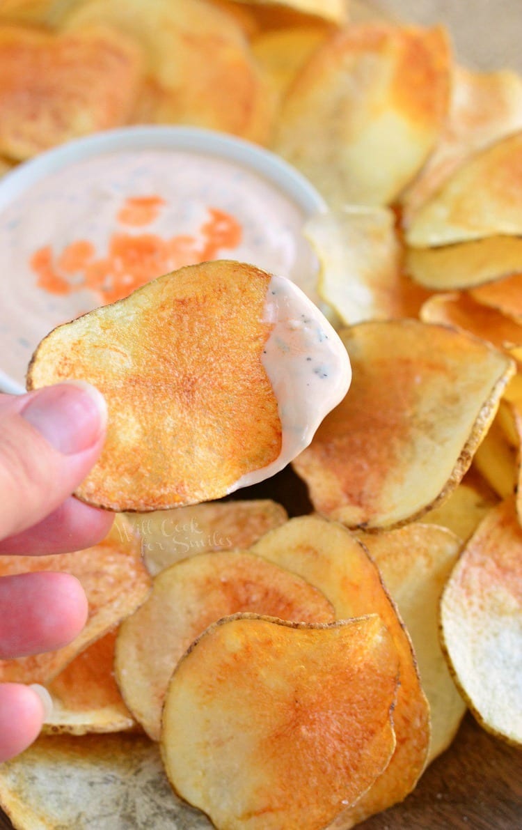 dipping Potato Chips with Buffalo Ranch Dip in a white bowl 