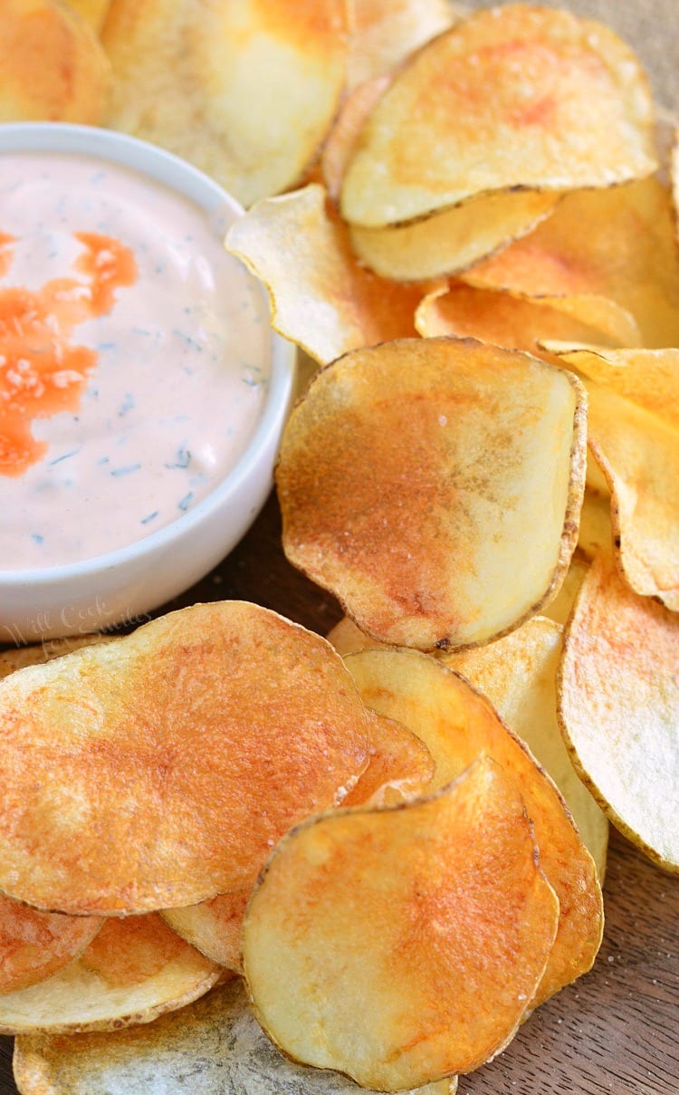 Homemade Potato Chips on a wood cutting board with Buffalo Ranch Dip in a white bowl 