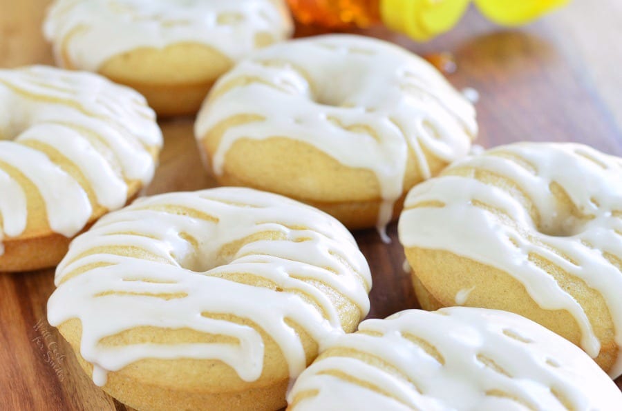 Honey Doughnuts stacked on a wood cutting board with honey bear bottle in the background  