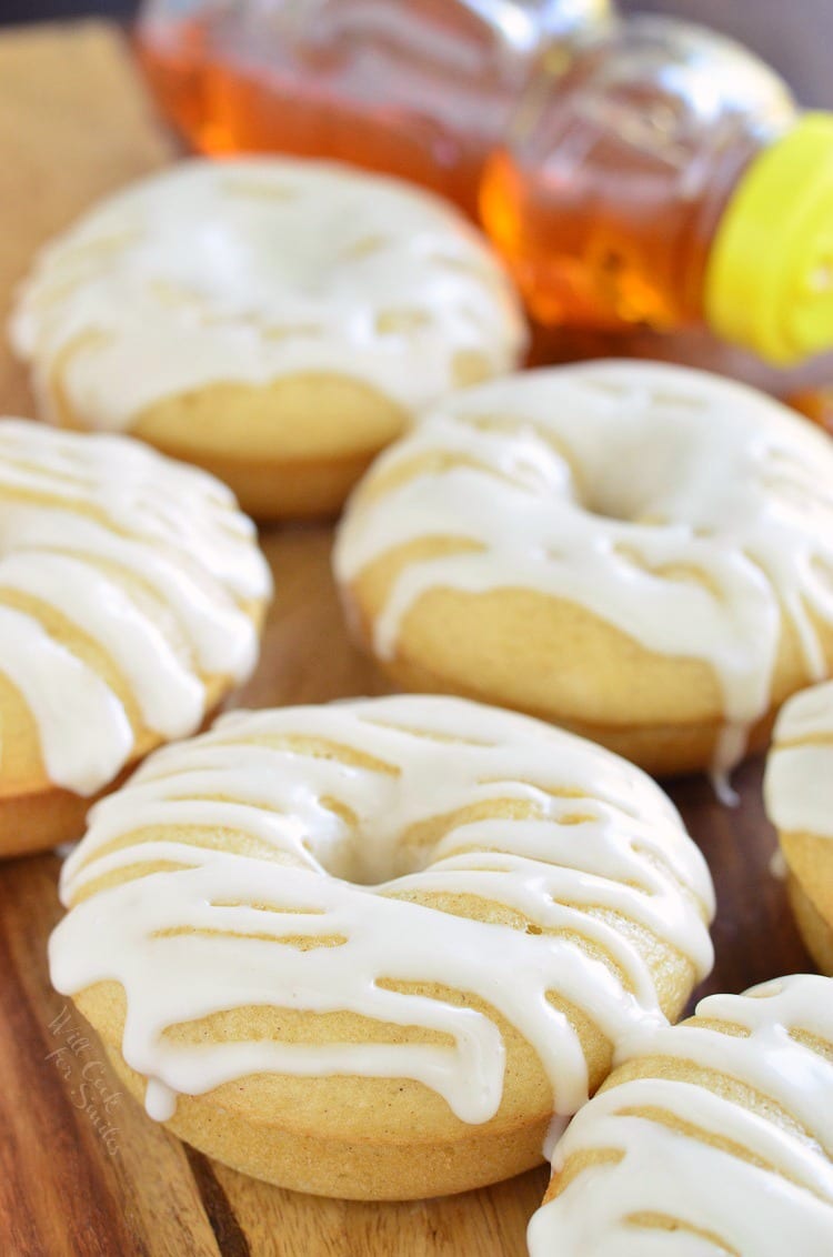 Honey Doughnuts stacked on a wood cutting board with honey bear bottle in the background  