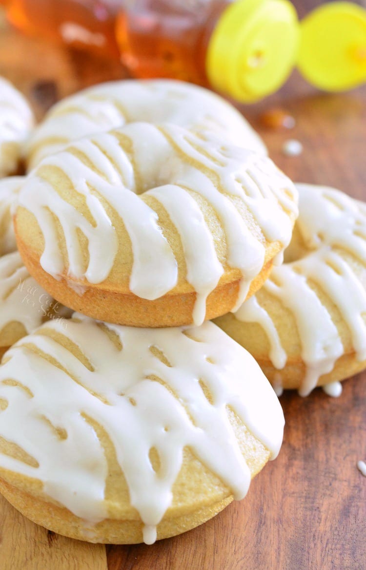 Honey Doughnuts stacked on a wood cutting board with honey bear bottle in the background  