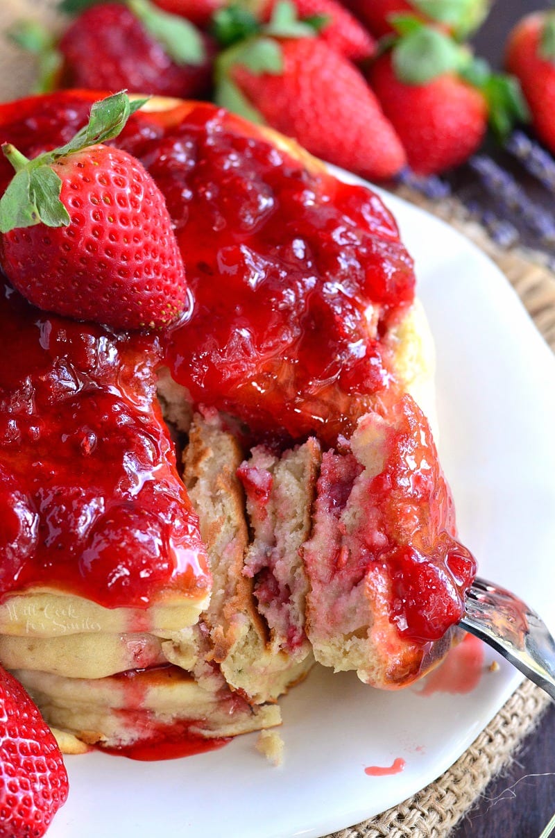 strawberry pancakes with strawberry sauce on top and a whole strawberry in the middle.