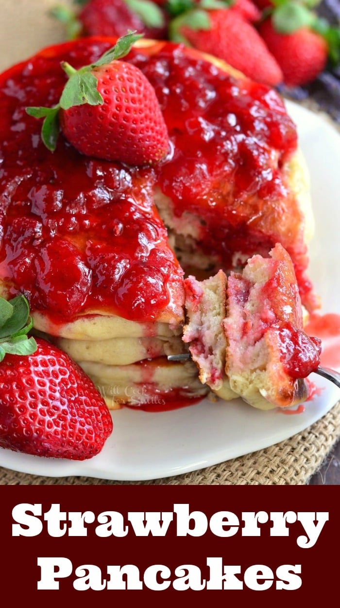 Strawberry Lavender Pancakes with strawberries and strawberries syrup on top on a white plate with a fork 