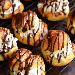 several Bailey's cream puffs on the wire rack filled with cream and drizzled in chocolate.