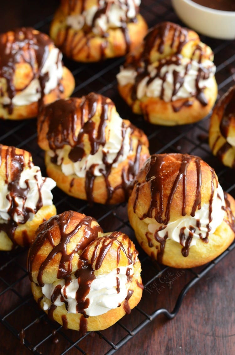several Bailey's cream puffs on the wire rack filled with cream and drizzled in chocolate.