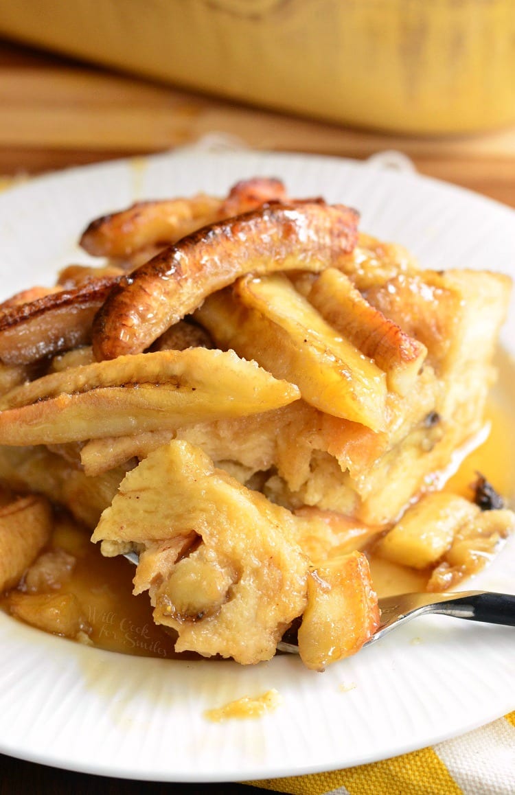 Bananas Foster Bread Pudding on a white plate with some on a fork 