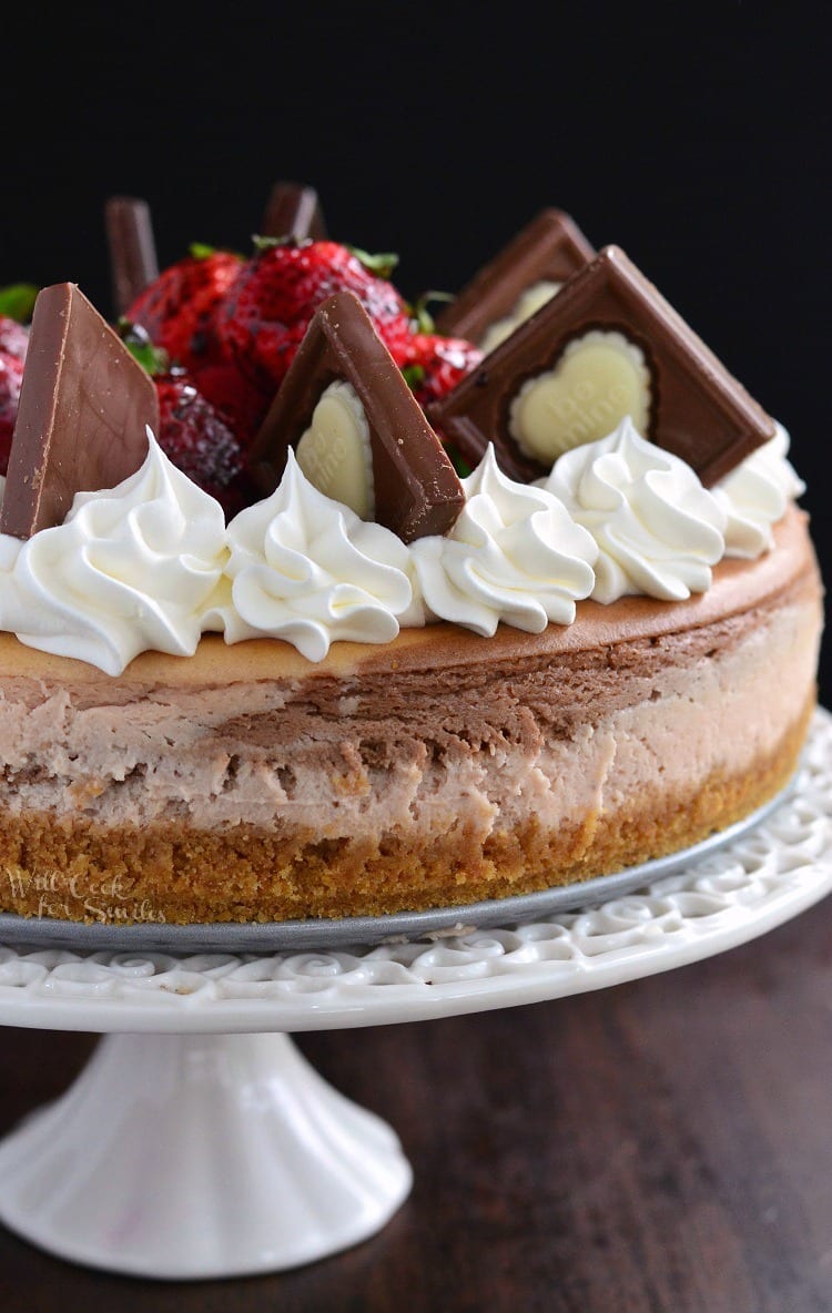 Chocolate Strawberry Marbled Cheesecake on a cake stand on a wood table 