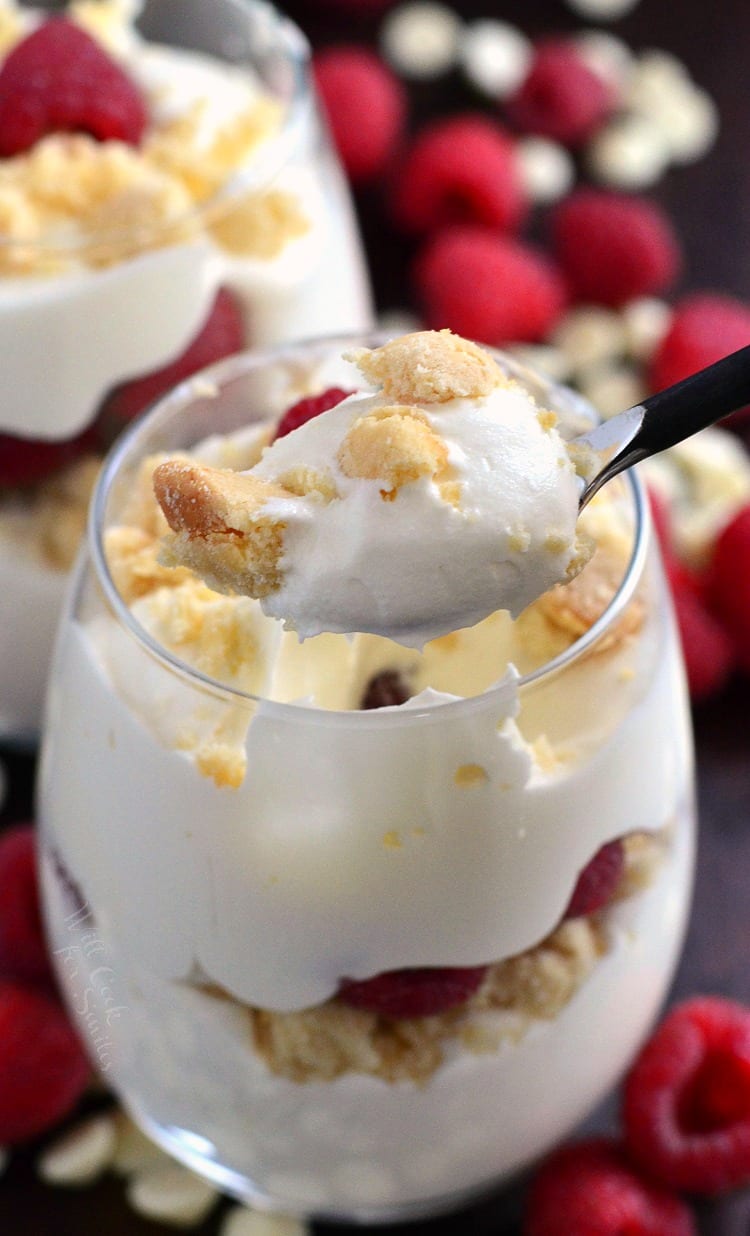 Raspberry White Chocolate Mousse Parfait in a stemless wine glass with a spoon full being lifted out 