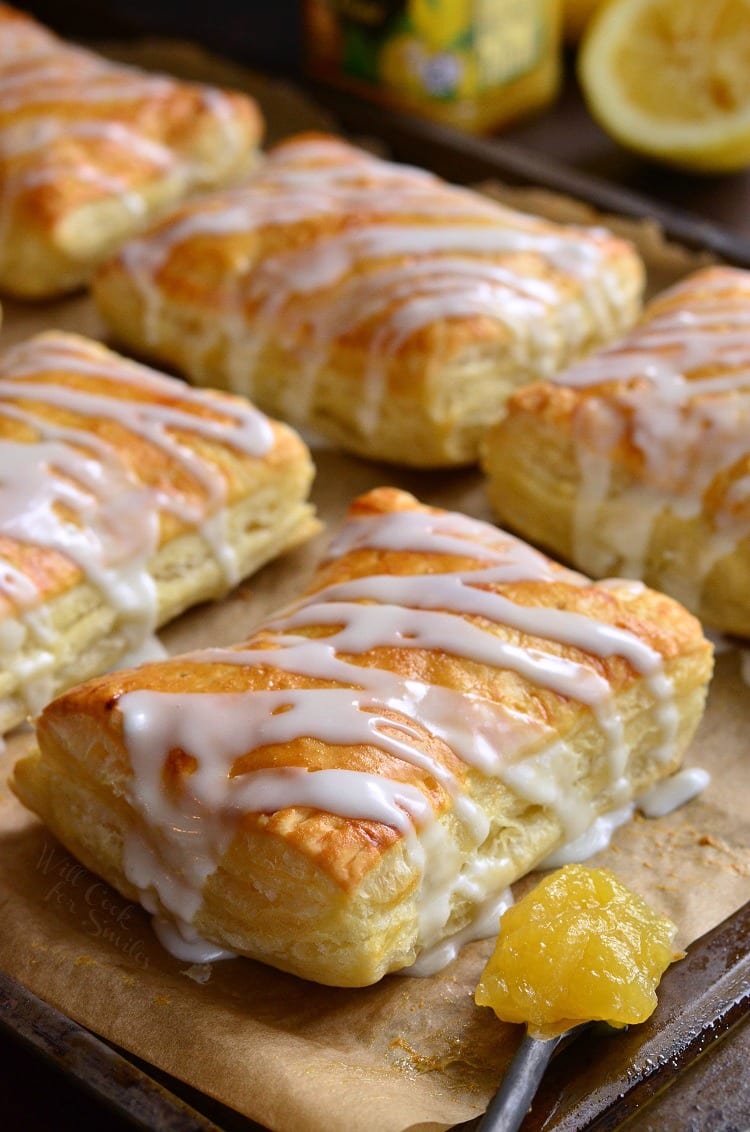 Lemon Cheesecake Hand Pies on a baking dish lined with butcher paper with a spoon full of lemon curd 