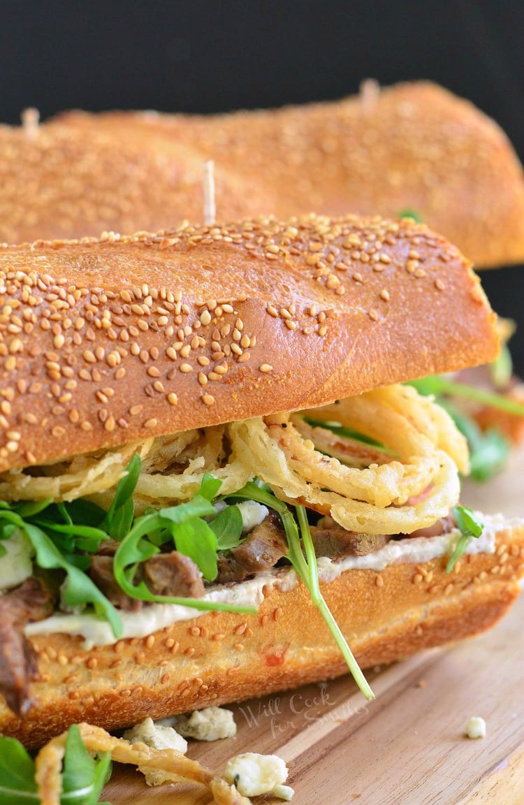 Onion Rings, Arugula and Steak sandwich on a wood cutting board 