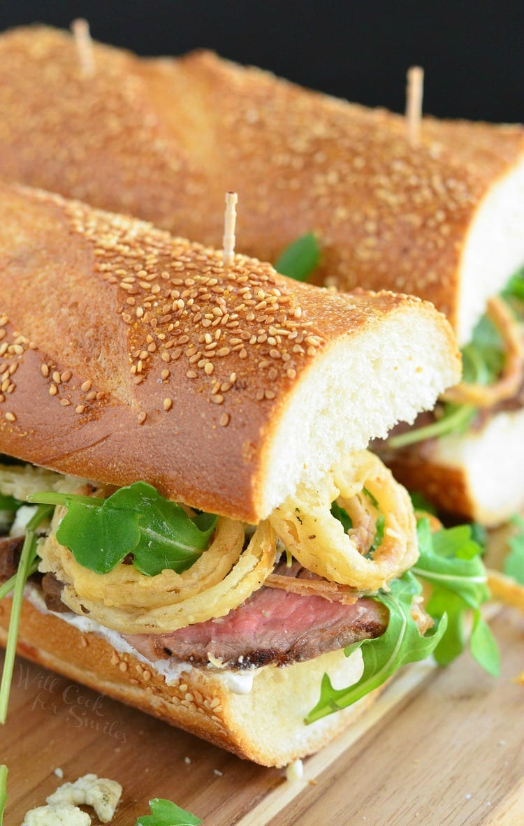 Onion Rings, Arugula and Steak sandwich on a wood cutting board 