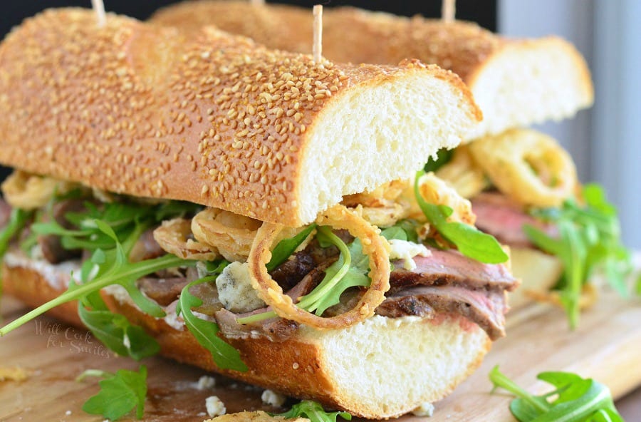 Onion Rings, Arugula and Steak sandwich on a wood cutting board 