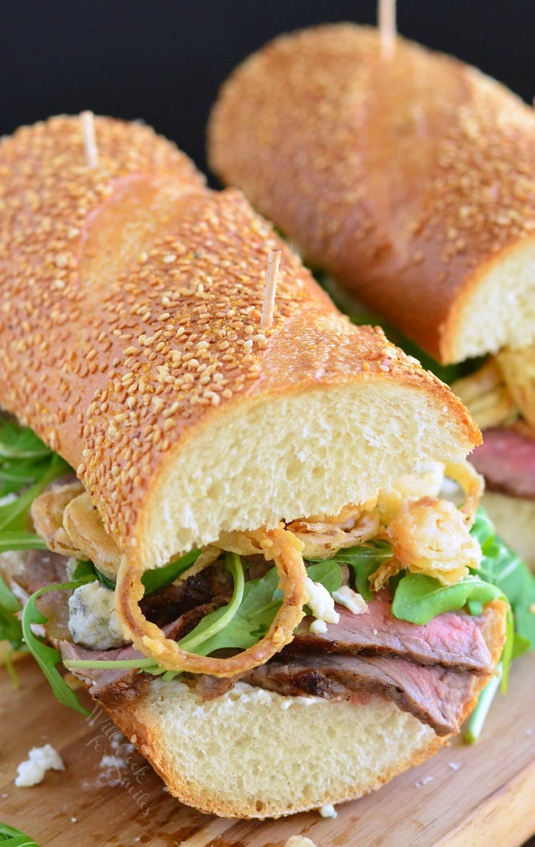 Onion Rings, Arugula and Steak sandwich on a wood cutting board 