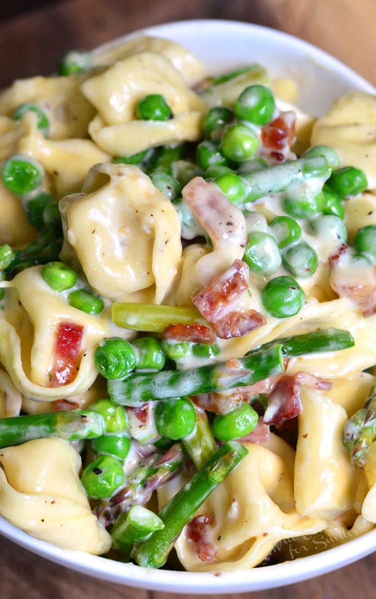 Creamy Spring Tortellini with Peas Asparagus and Bacon in a white bowl 