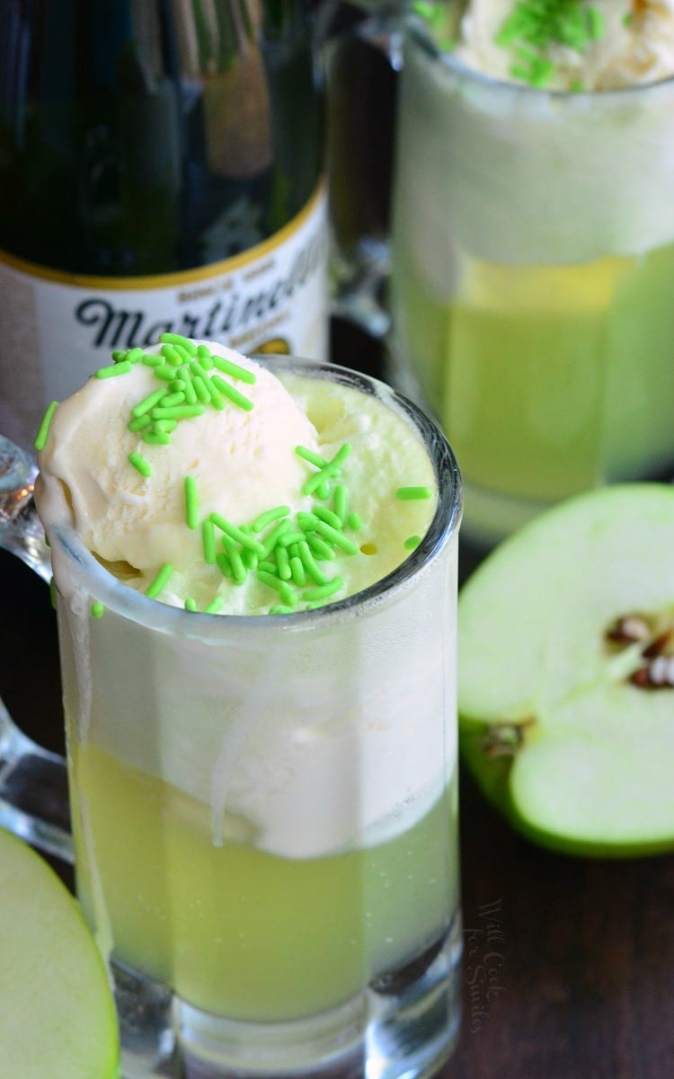 Green Apple Ice Cream Soda Float in a glass mug with Martinelli's Sparkling Apple Cider in the background a sliced apples on a table 