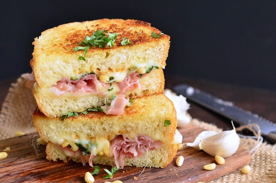 Italian Garlic Bread Grilled Cheese with ham cut in half on a cutting board 