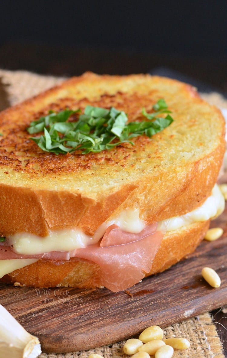 Italian Garlic Bread Grilled Cheese with parsley on top as garnish on a cutting board with pine nuts around 