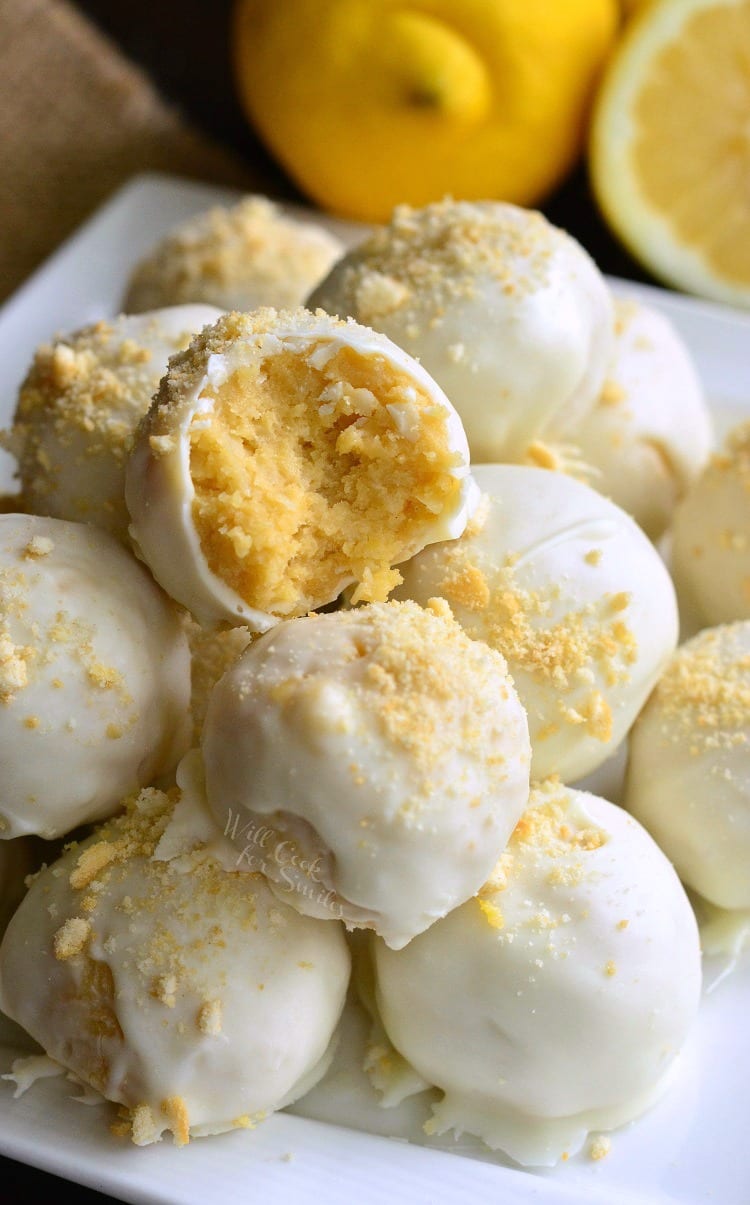 Lemon Oreo Coconut Cookie Truffles on a white plate with a bite taken out of one and lemons in the background 
