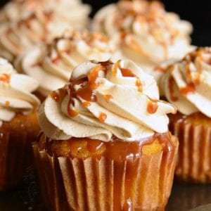 several carrot cake cupcakes on a baking sheet closeup on one with caramel frosting and caramel drizzle.
