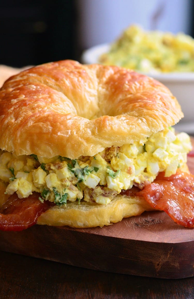 Bacon and Green Onion Egg Salad on a croissant on a cutting board  