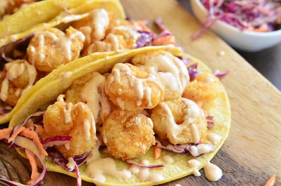 horizonal photo of crispy shrimp in a corn tortilla with sour cream on top.