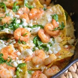 nachos in cast iron pan with cheese and shrimp.