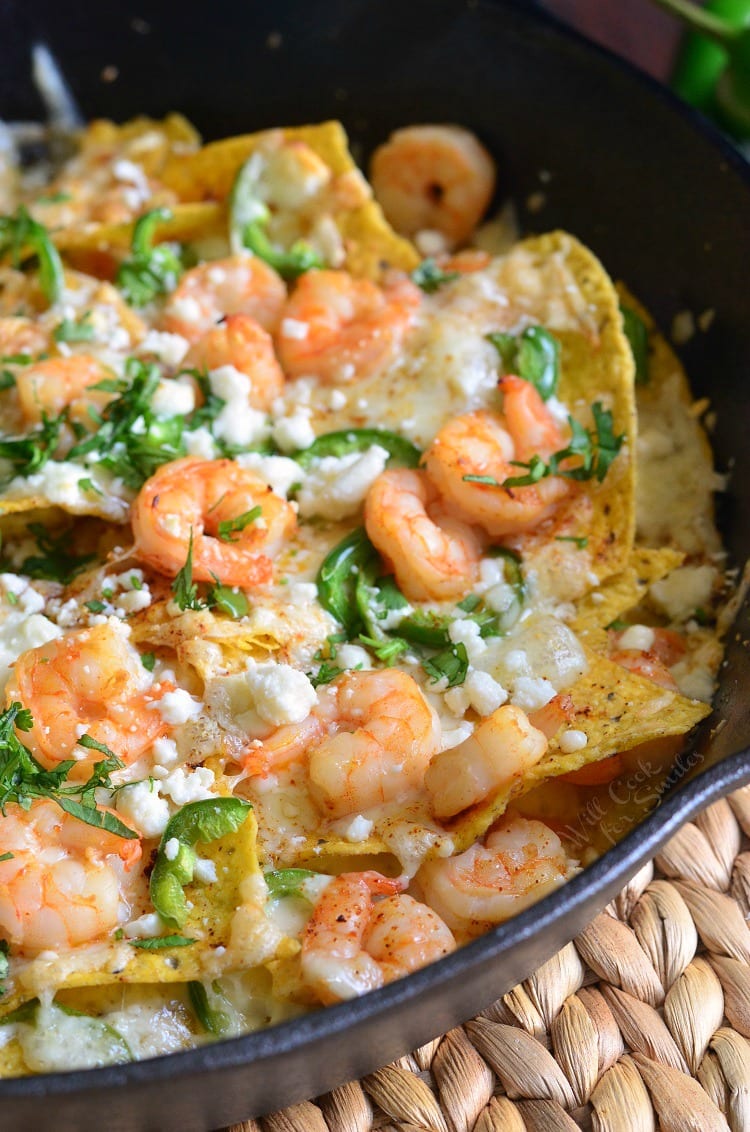 nachos in cast iron pan with cheese and shrimp.
