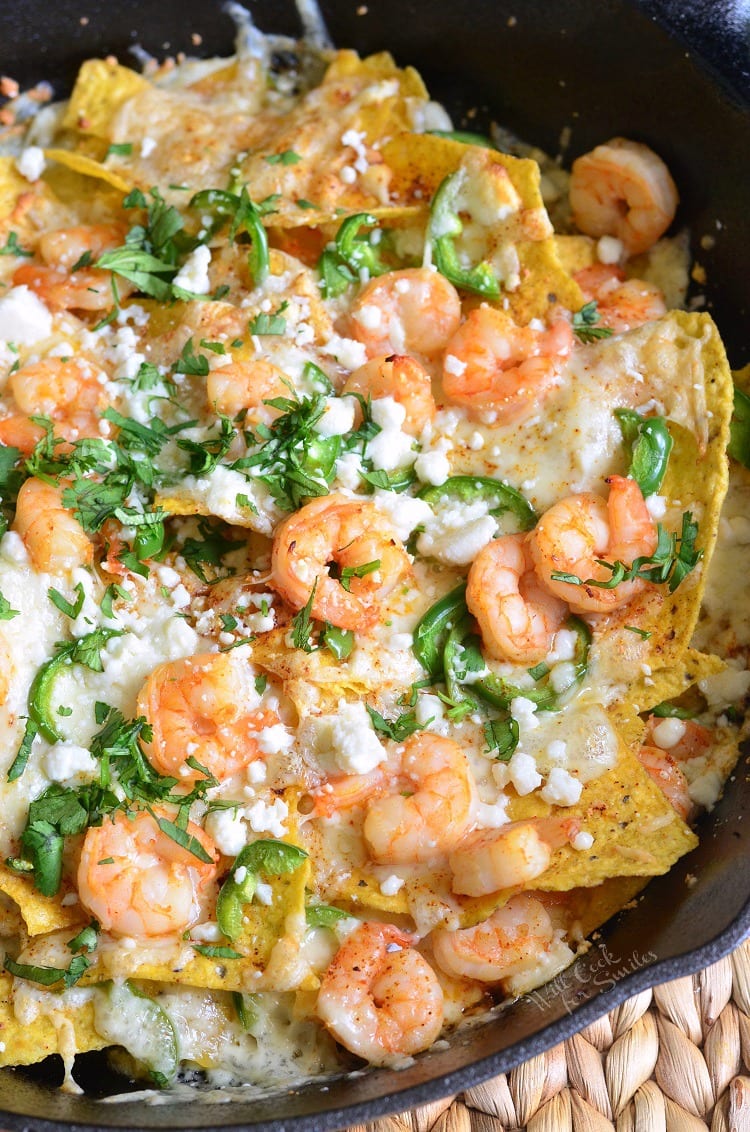 Shrimp Nachos in a cast iron pan with jalapenos and cilantro on top.