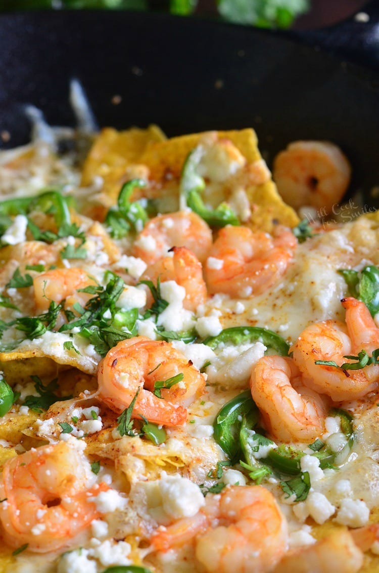 nachos with shrimp and cheese and jalapeno peppers on top.