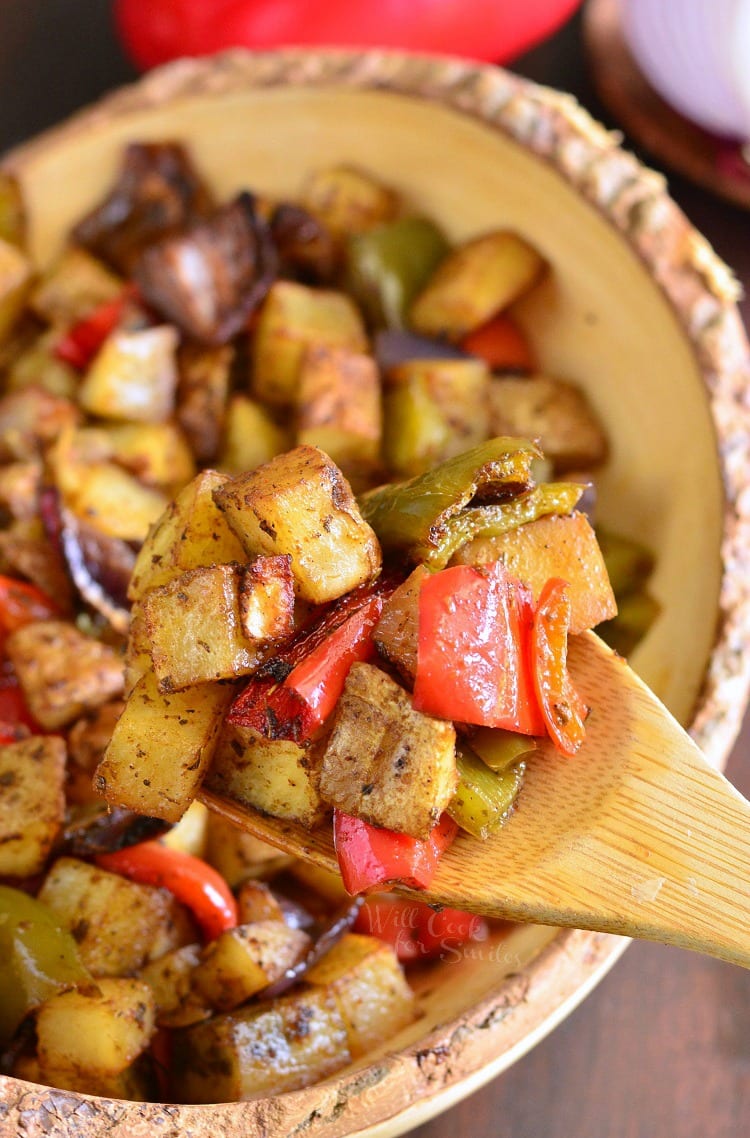 Southwest Roasted Potatoes in a yellow bowl with a wooden spoon scooping some out 