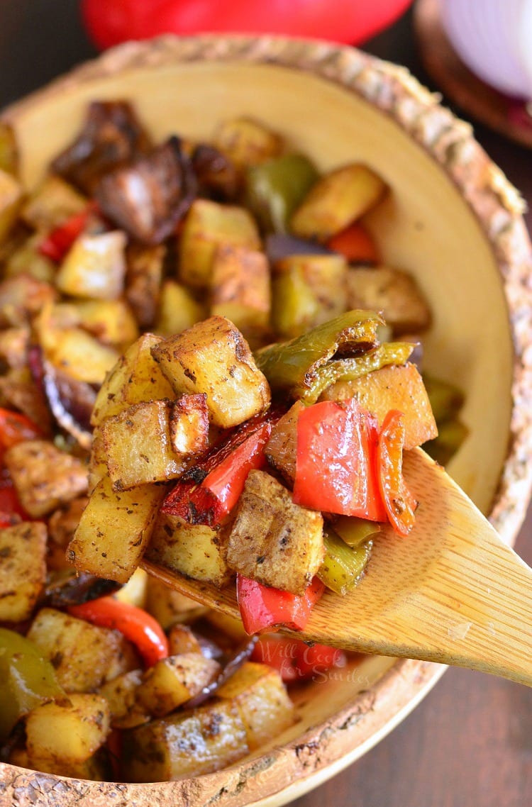 Southwest Roasted Potatoes in a yellow bowl with a wooden spoon scooping some out 