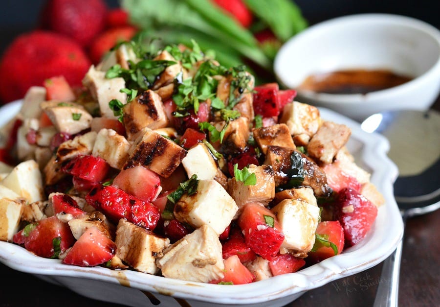 Balsamic Strawberry Chicken Salad in a white serving bowl with dressing in the background 