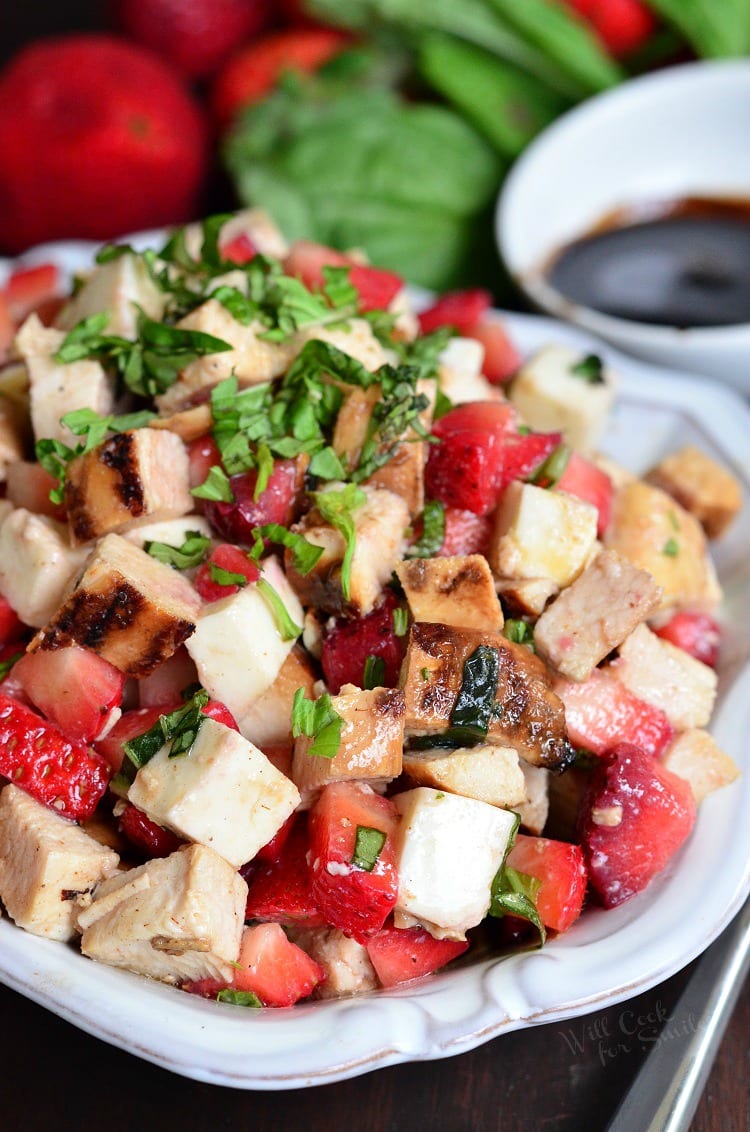 Balsamic Strawberry Chicken Salad in a white serving bowl  with strawberries in the background 