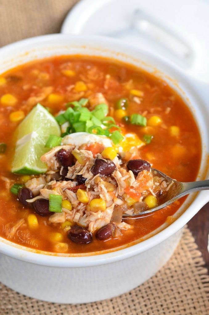 spooning out some chicken tortilla soup from white bowl.