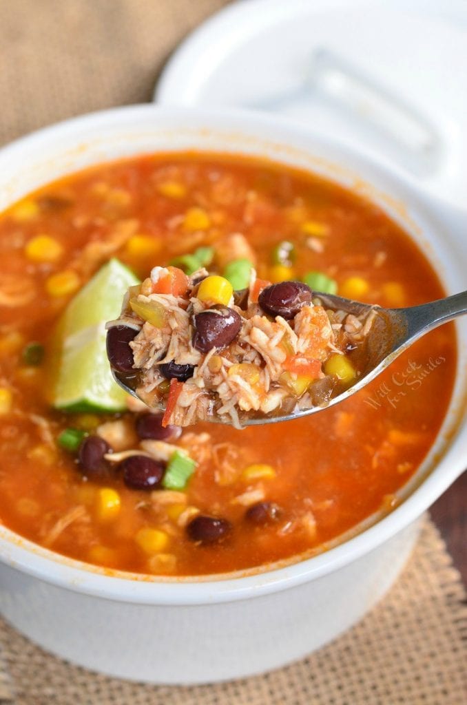 holding a spoonful of soup over the bowl full of soup.