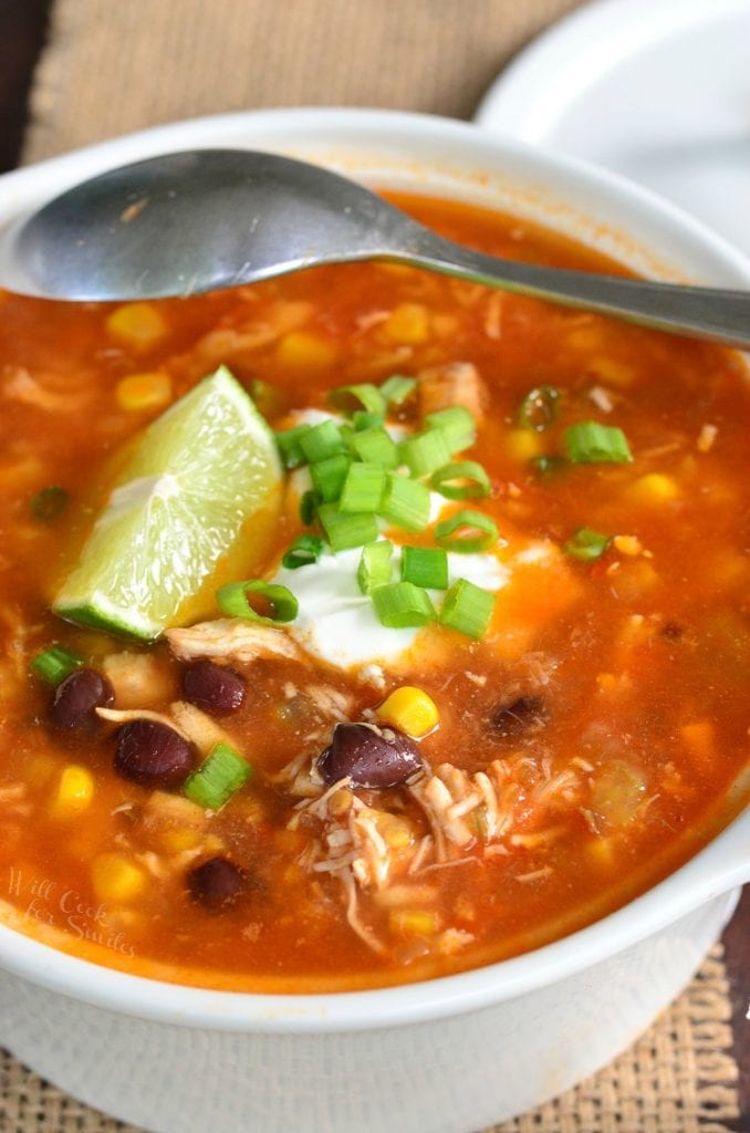 closeup of chicken tortilla soup topped with lime and sour cream.