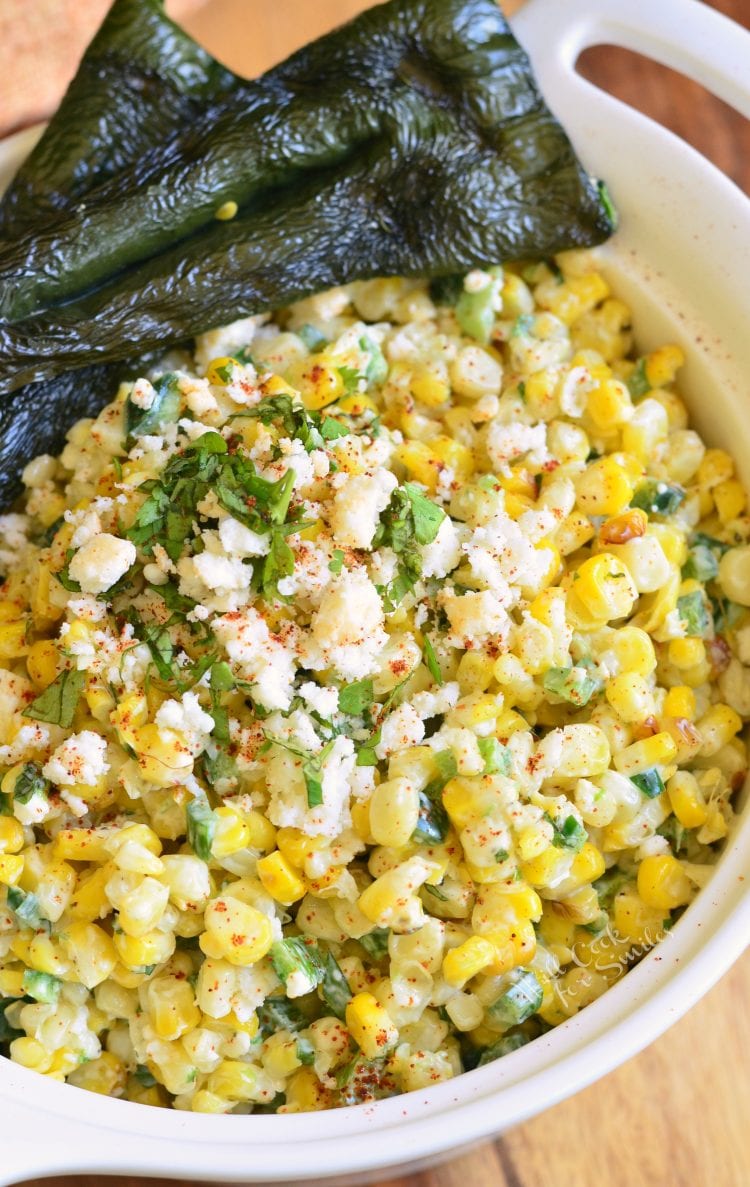 view from the top of corn salad in a whote bowl with roasted poblano peppers next to it