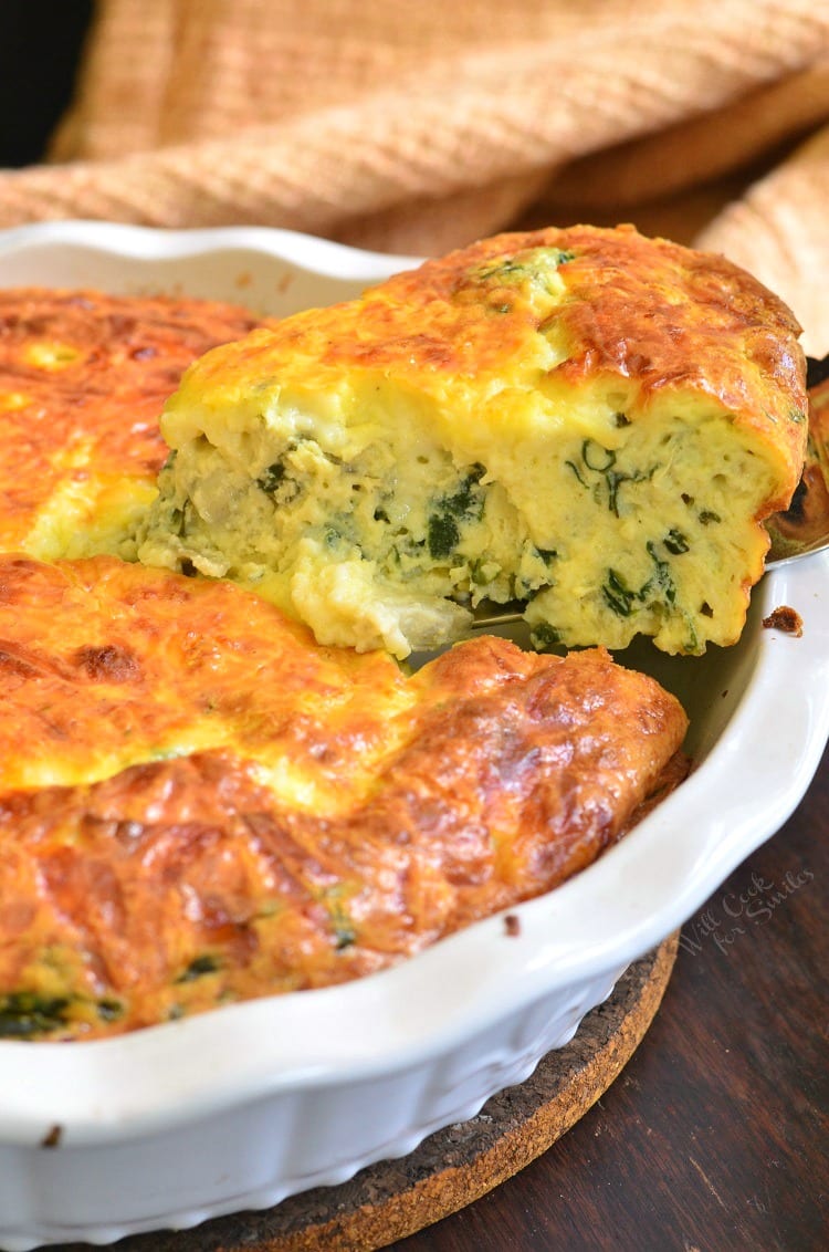 Crustless quiche in a white pie dish with a slice being cut out.