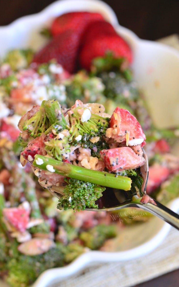 Strawberry Asparagus Broccoli Salad being scooped out of white bowl with a spoon 