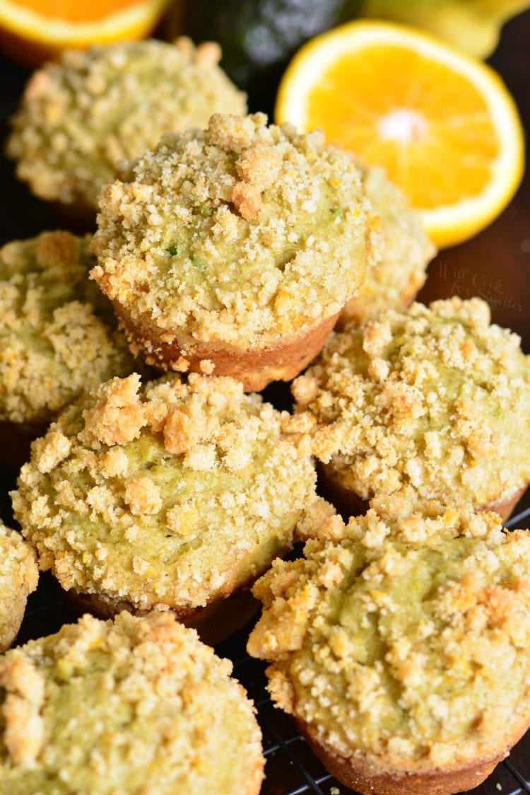 Avocado Banana Muffins with Orange Streusel stacked up on cutting board, orange in background