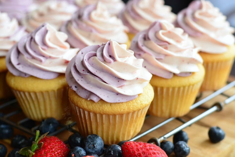 Berry Filled Cupcakes with Strawberry and Blueberry Marble Frosting on a cooling rack with blueberries and strawberries 