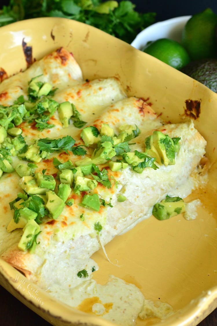 vegetable enchiladas in a casserole dish with 2 taken out of the dish