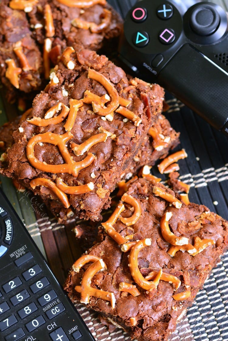 Pretzel Bacon Brownies on a table with a tv remote and playstation remote 