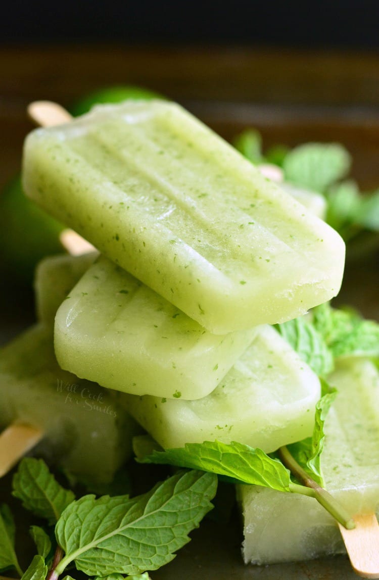 Honeydew Mojito Popsicles stacked on a cutting board with mint leaves 