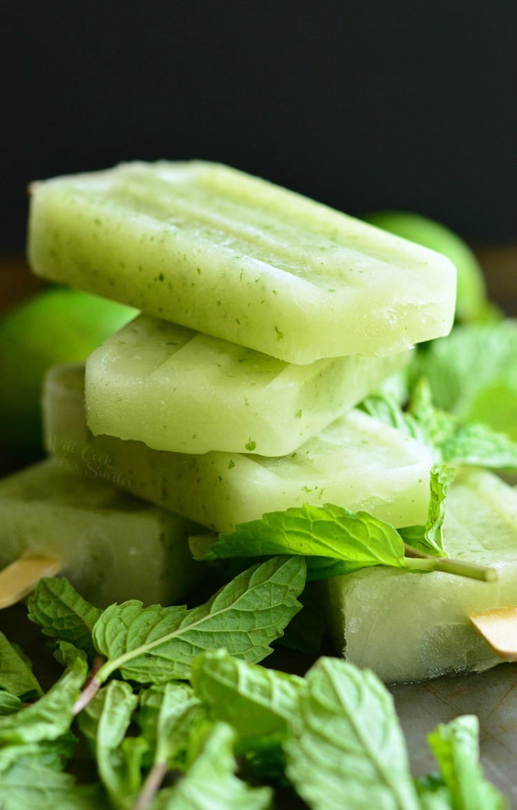 Honeydew Mojito Popsicles stacked up on a cutting board with mint around 