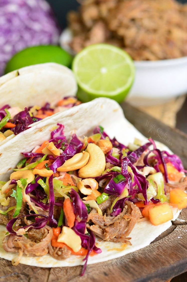 Pulled Pork Tacos with Tropical Slaw on a cutting board with a lemon in the background 
