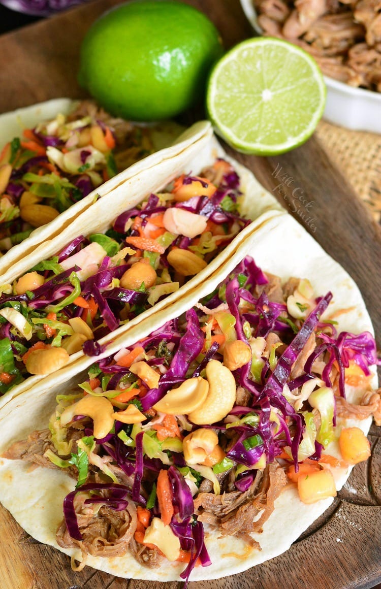 3 Pulled Pork Tacos with Tropical Slaw on a cutting board with a lime 